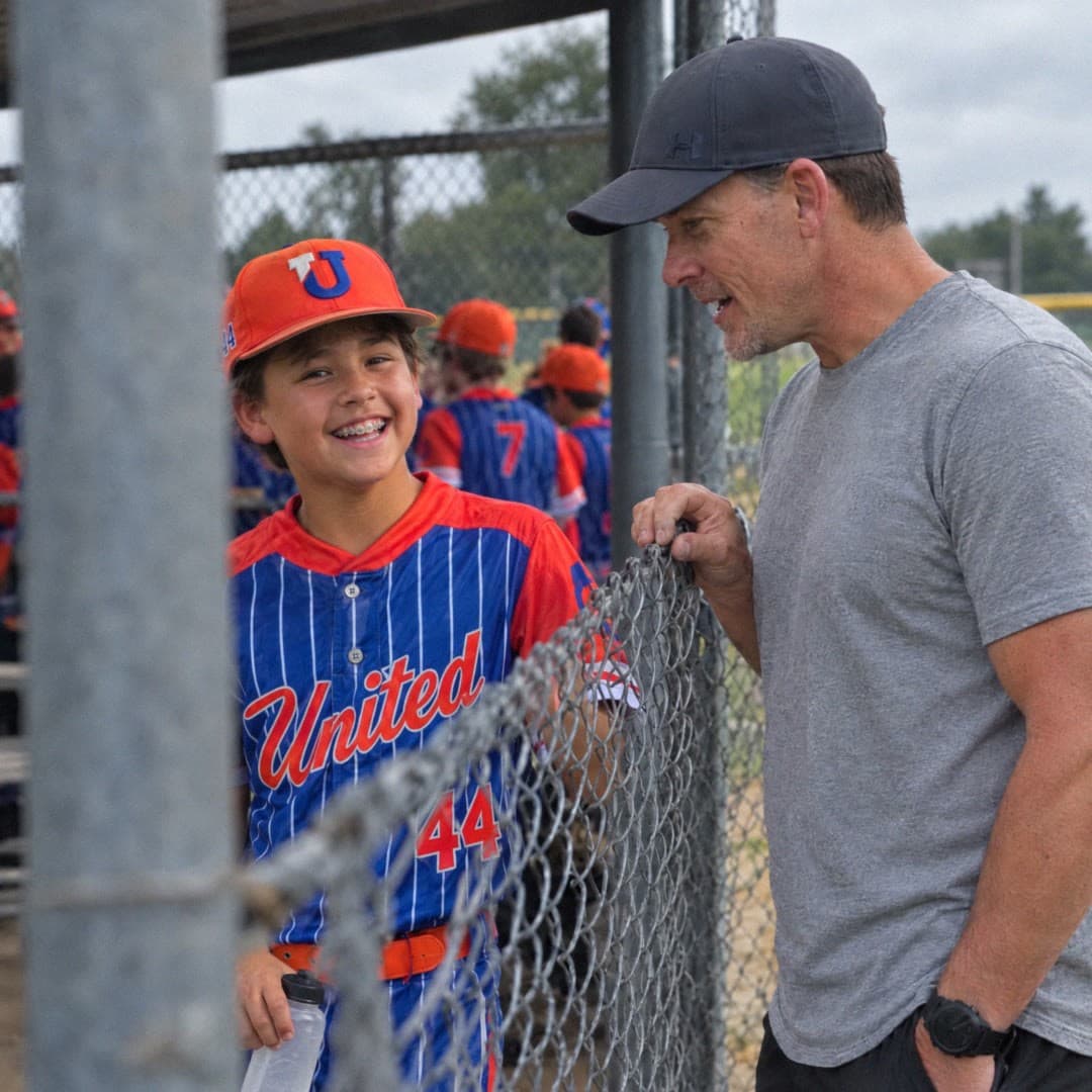 Dr. Russ Beach talking with his son Greyson at the dugout fence
